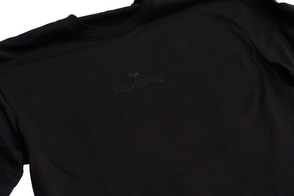 A black oversized T-shirt with a logo on the chest, displayed against a white background.