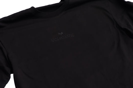 A black oversized T-shirt with a logo on the chest, displayed against a white background.